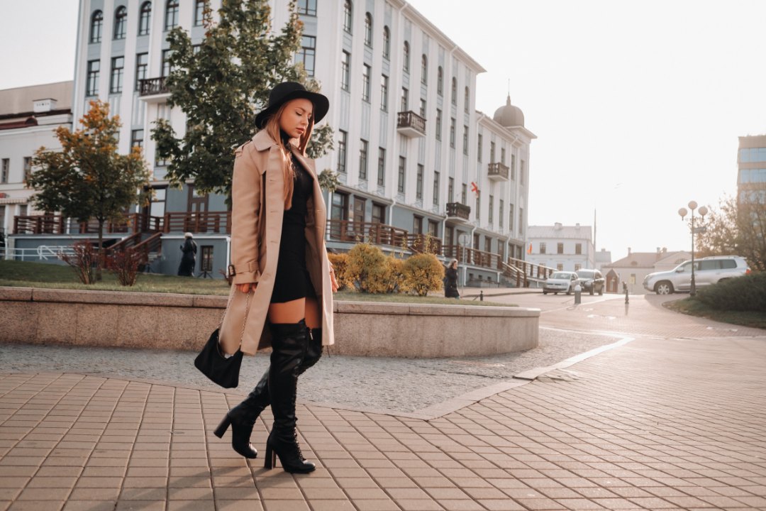 Mujer con gabardina y botas paseando por la ciudad